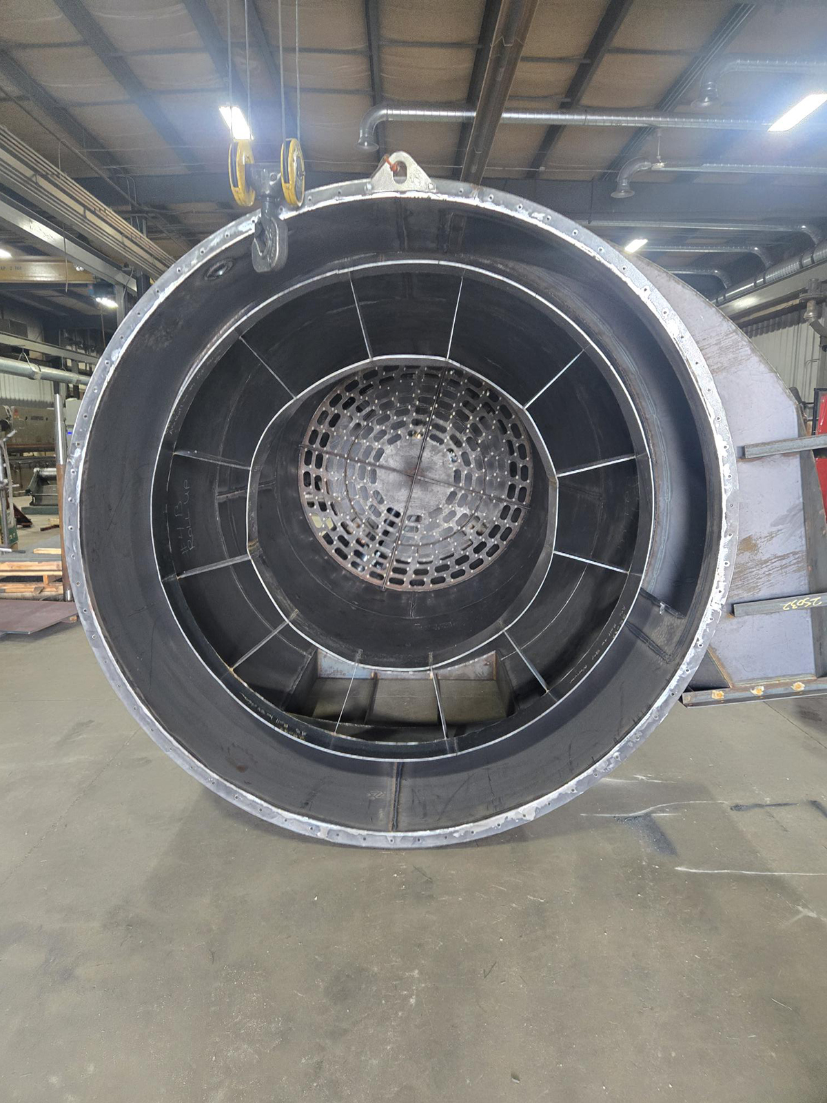 design-build-006-new A large-scale industrial machinery assembly featuring a horizontal cylindrical housing integrated with a vertical conical hopper and reinforced circular base at Lee Industries.