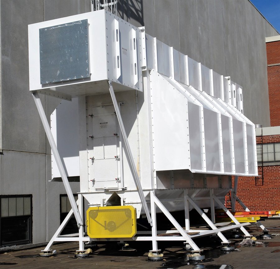 design-build003 A large, custom-fabricated white industrial dust collection system or air filtration unit installed on a rooftop, featuring a specialized support frame and safety shielding.