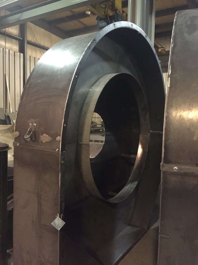 design-build009 A custom-fabricated, heavy-duty steel fan housing or centrifugal blower casing featuring a large circular intake and reinforced structural base, staged in the Lee Industries workshop.
