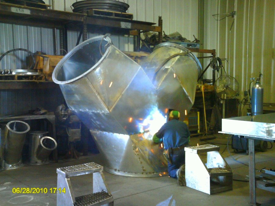 ductwork002 A technician performs precision welding on a massive Y-shaped industrial metal duct segment inside the fabrication shop at Lee Industries of Little Falls, MN.