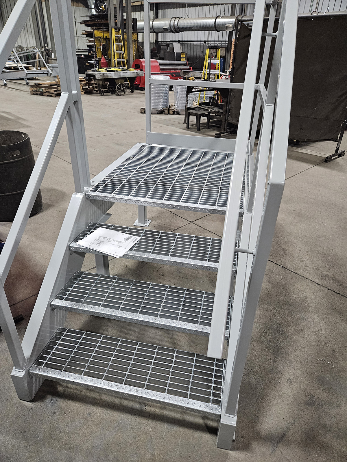 metalfab-001-new A high-durability, custom-fabricated industrial access platform featuring safety stairs with open-grate treads and a reinforced steel mezzanine structure at Lee Industries.